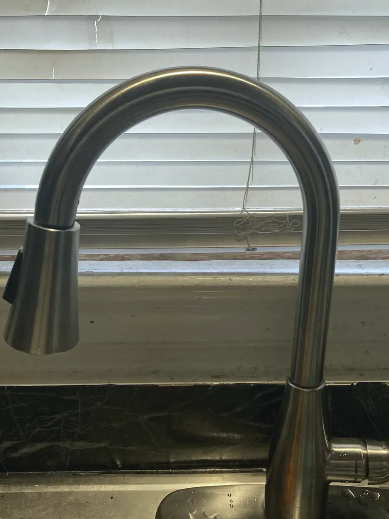 A new brushed-nickel pull-down kitchen faucet at a window